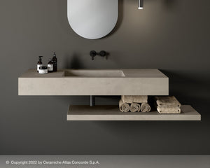 A modern porcelain washbasin with a wall-mounted design, featuring a gray color and integrated with bathroom accessories such as soap dispensers and a towel, set against a dark background.